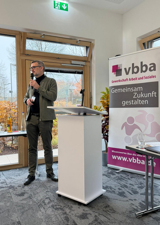 Christian Löschner mit Mikrofon neben dem Rednerpult