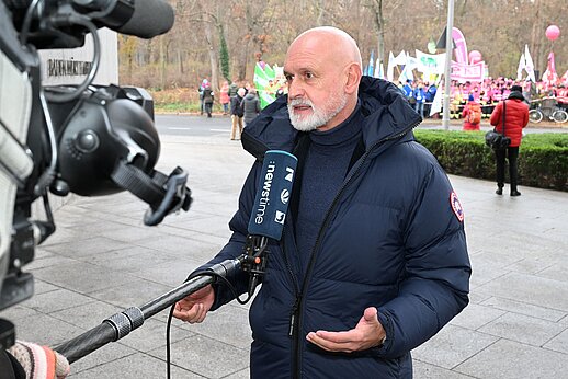 Volker Geyer beim Pressegespräch, im Hintergrund die Streikteilnehmer.