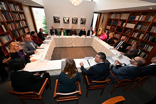 Auf dem Bild sind Tische zu einem Viereck gestellt, daran sitzen die verhandelnden Parteien.