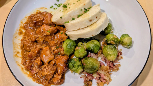 Teller mit leckerem Gulasch mit Knödeln und Rosenkohl